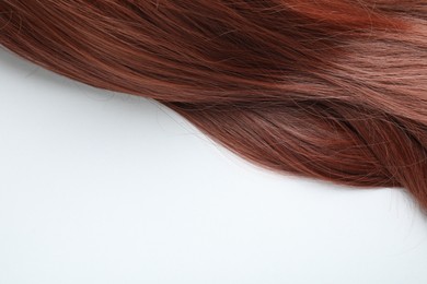 Photo of Auburn hair strand on white background, top view. Space for text