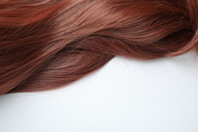 Photo of Auburn hair strand on white background, top view. Space for text