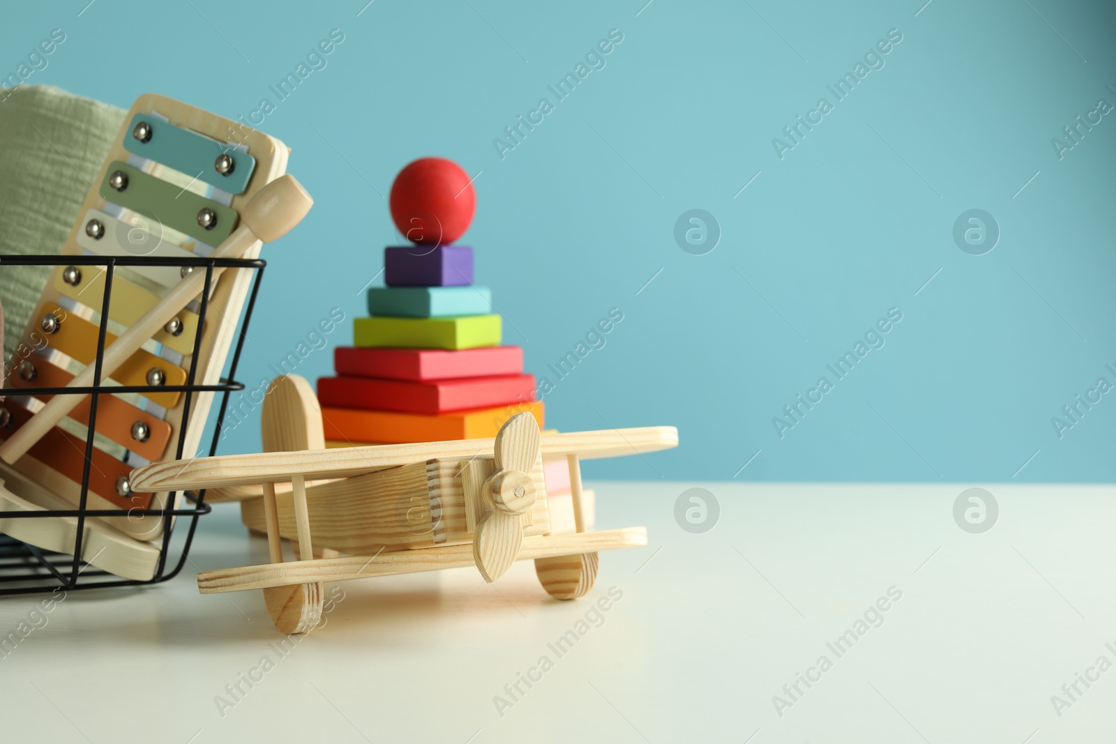Photo of Different cute toys on white table against light blue background. Space for text