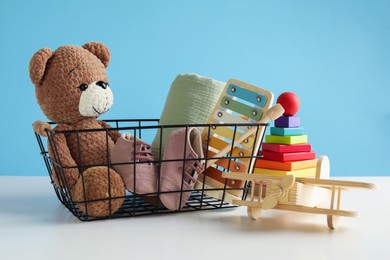 Photo of Different cute toys on white table against light blue background