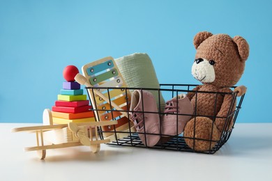 Photo of Different cute toys on white table against light blue background