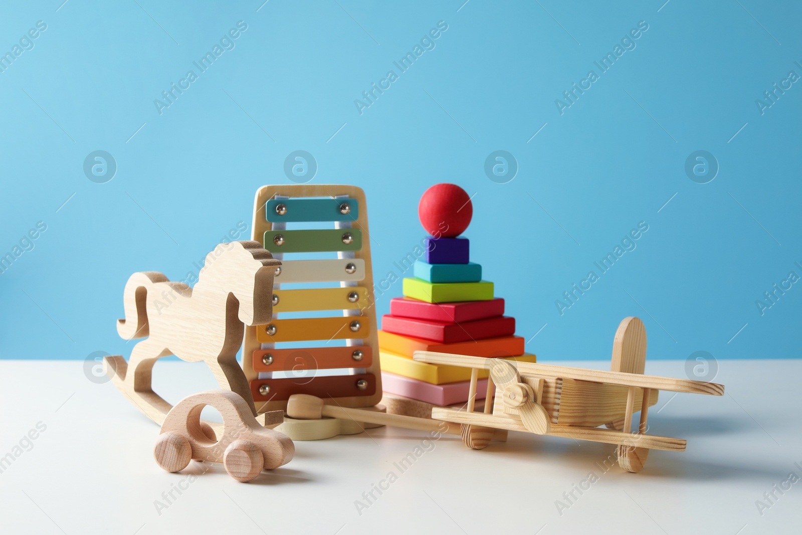 Photo of Different cute toys on white table against light blue background