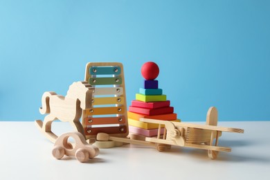 Photo of Different cute toys on white table against light blue background