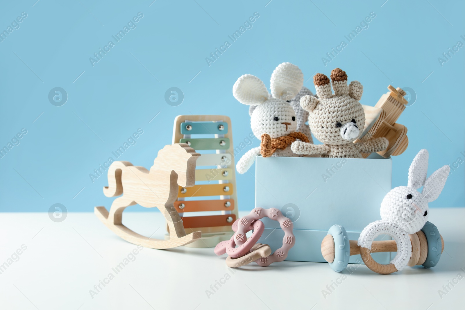 Photo of Different cute toys on white table against light blue background. Space for text
