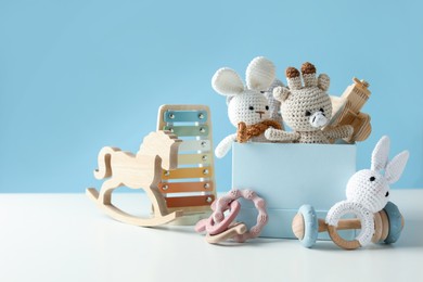 Photo of Different cute toys on white table against light blue background. Space for text
