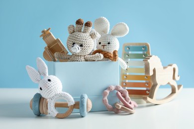 Photo of Different cute toys on white table against light blue background