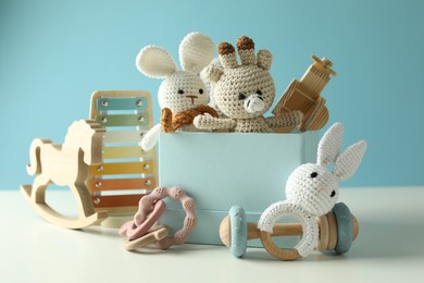 Photo of Different cute toys on white table against light blue background