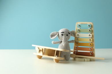 Photo of Different cute toys on white table against light blue background. Space for text