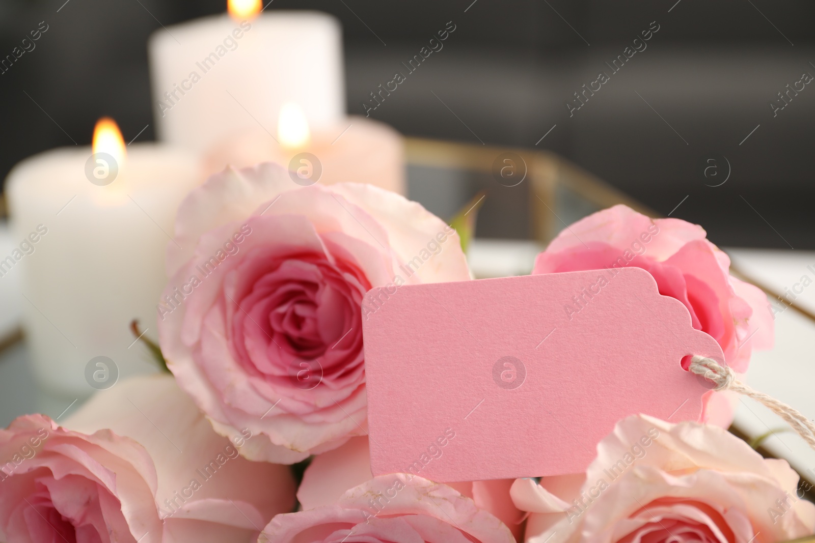 Blank card, roses and burning candles on table indoors, closeup Photo of Blank card, roses and burning candles on table indoors, closeup