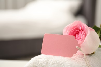 Photo of Blank card and rose on towel indoors, closeup. Space for text