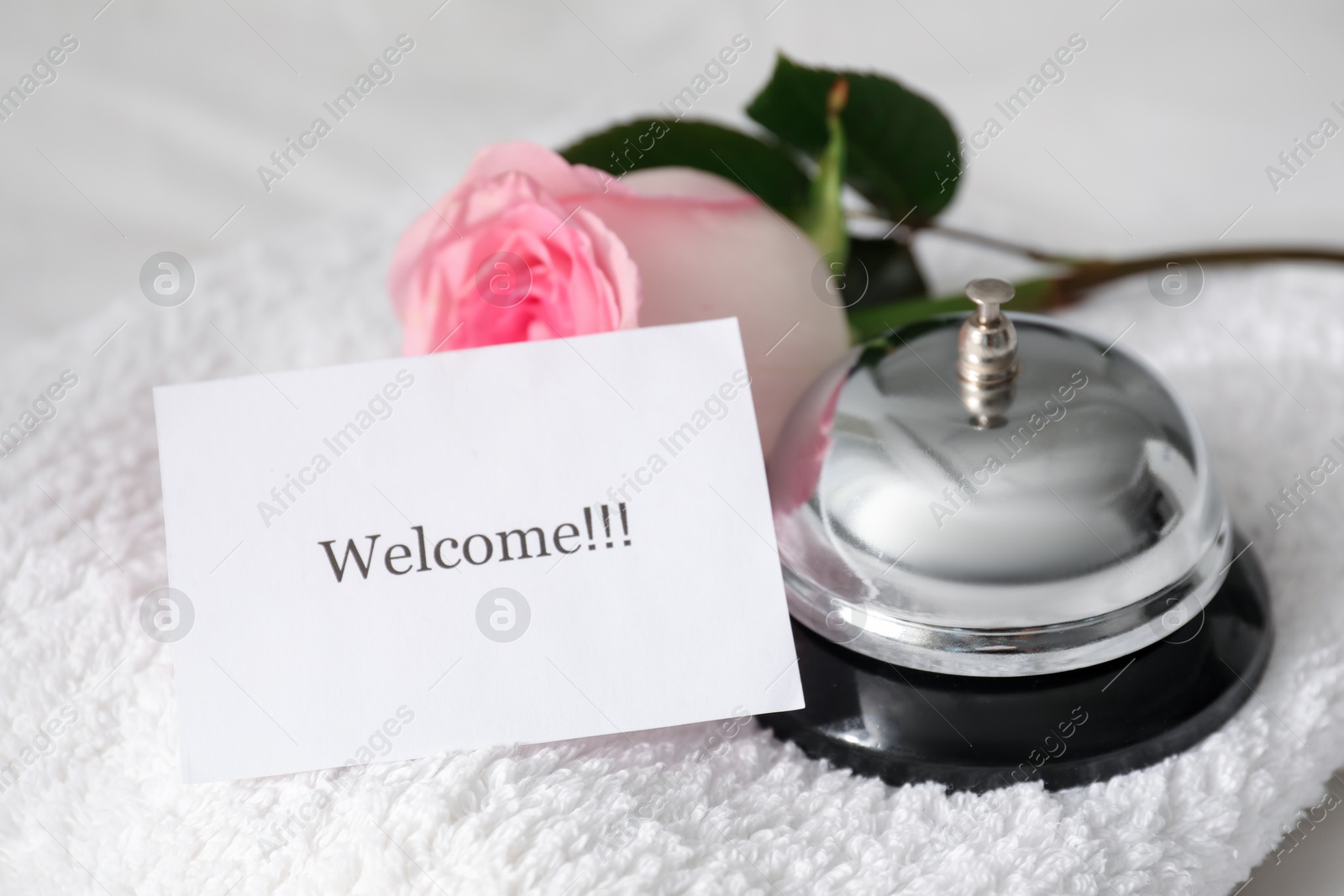 Card with word Welcome, desk bell, rose and towel on white table, closeup Photo of Card with word Welcome, desk bell, rose and towel on white table, closeup