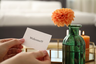 Photo of Woman holding card with word Welcome indoors, closeup