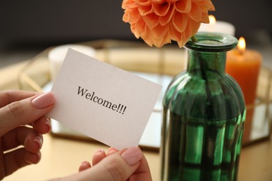 Photo of Woman holding card with word Welcome indoors, closeup