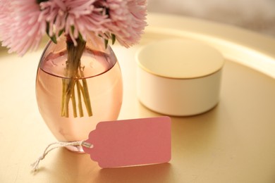 Photo of Blank card, vase with flowers and candle on table indoors, closeup