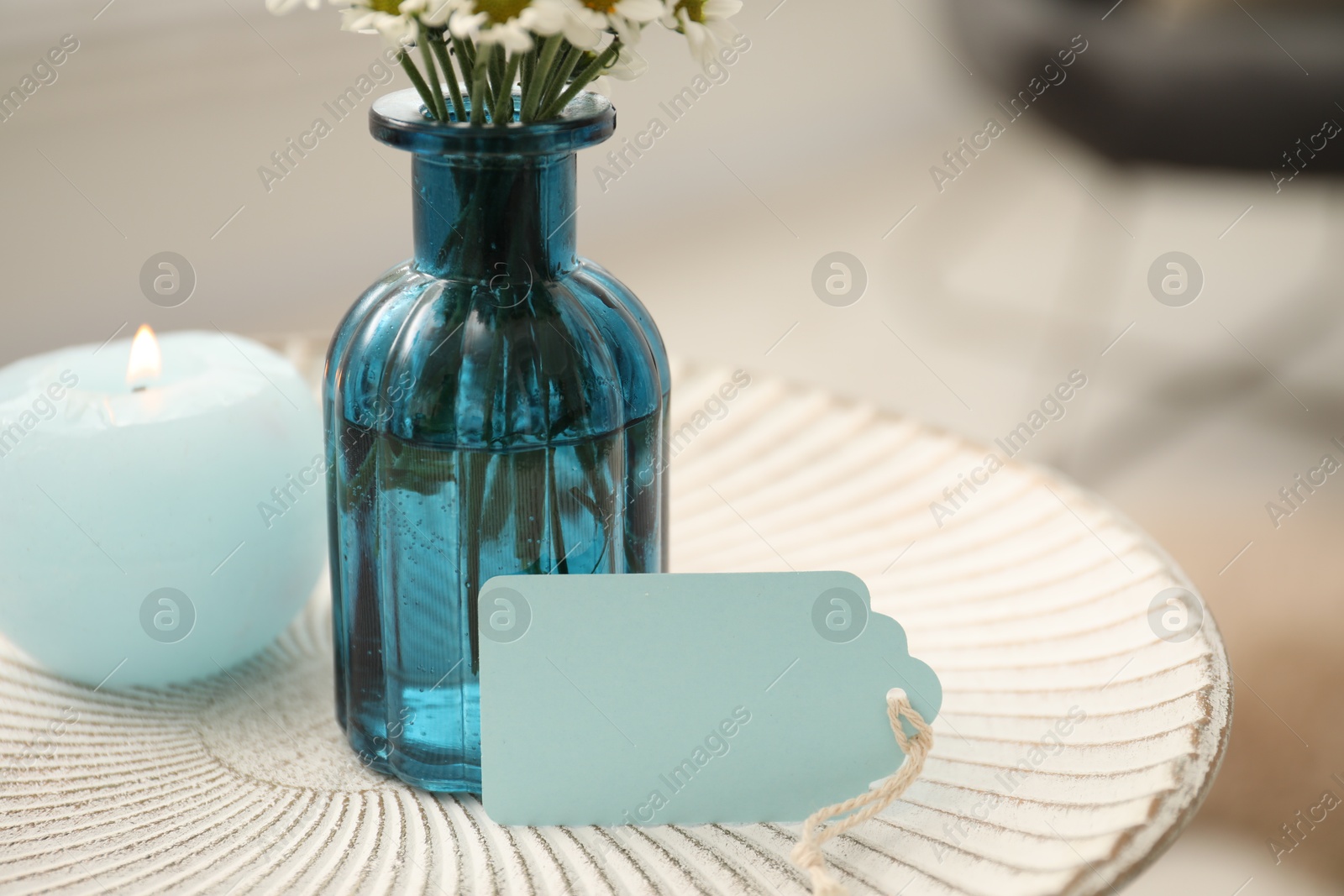Photo of Blank card, vase with flowers and candle on table indoors, closeup. Space for text