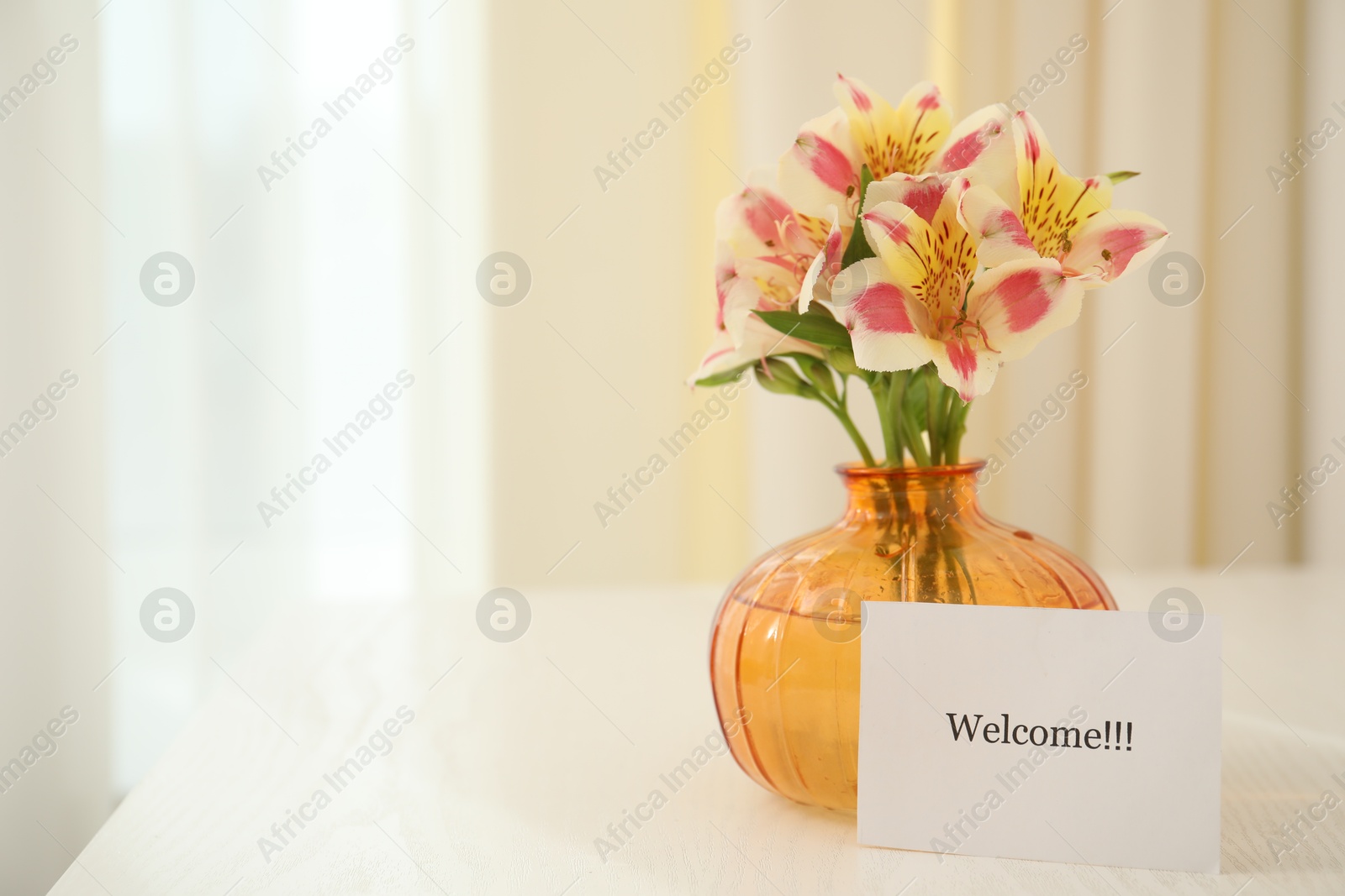 Photo of Card with word Welcome and vase with flowers on white table indoors. Space for text