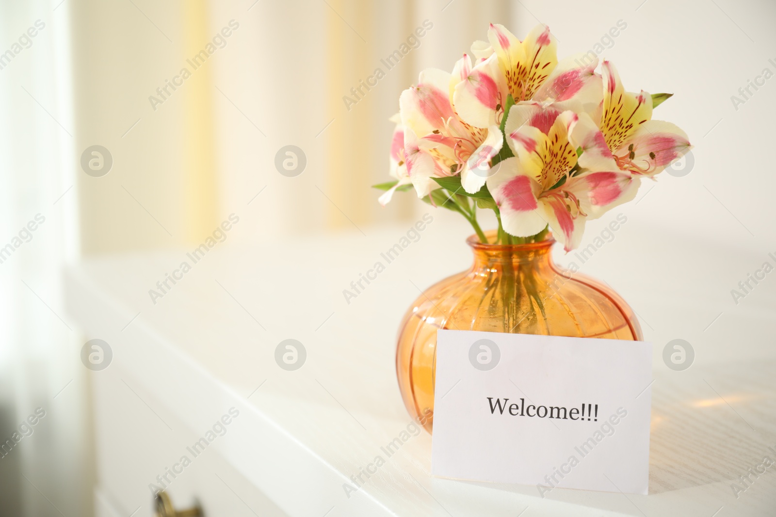 Photo of Card with word Welcome and vase with flowers on white table indoors. Space for text