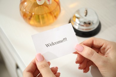Photo of Woman holding card with word Welcome indoors, closeup
