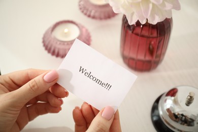 Photo of Woman holding card with word Welcome indoors, closeup