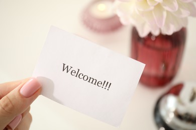 Photo of Woman holding card with word Welcome indoors, closeup