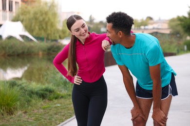 Photo of Smiling runners resting outdoors. Space for text