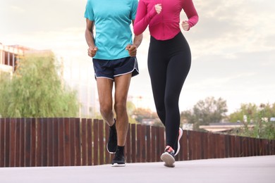 Photo of Couple in sportswear running outdoors, closeup. Healthy lifestyle