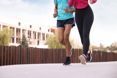 Photo of Couple in sportswear running outdoors, closeup. Space for text