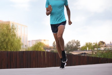 Photo of Man in sneakers running outdoors, closeup. Healthy lifestyle