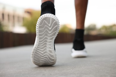 Photo of Man in sneakers running outdoors, closeup. Healthy lifestyle