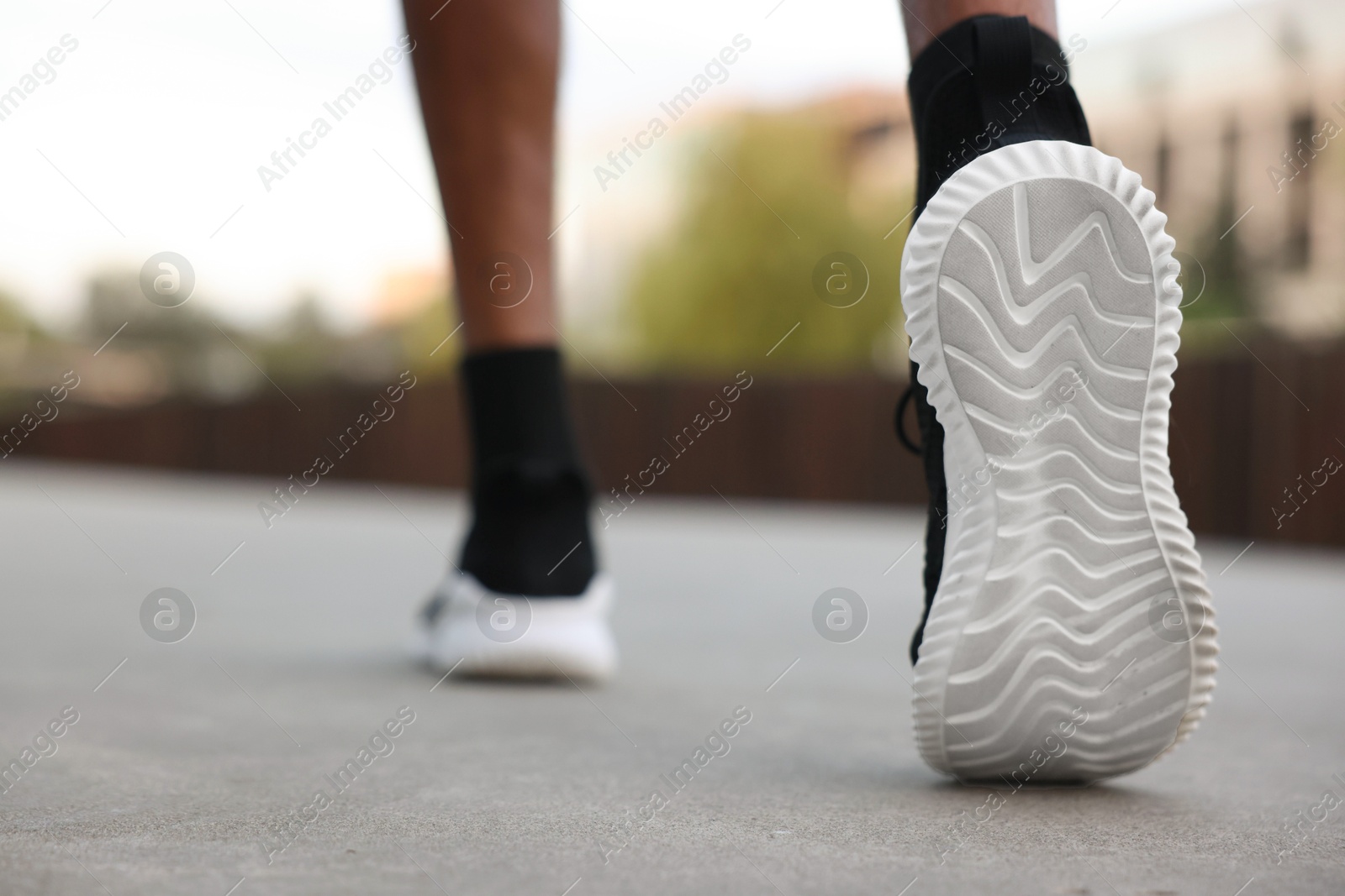 Photo of Man in sneakers running outdoors, closeup. Healthy lifestyle
