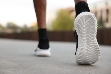 Photo of Man in sneakers running outdoors, closeup. Healthy lifestyle