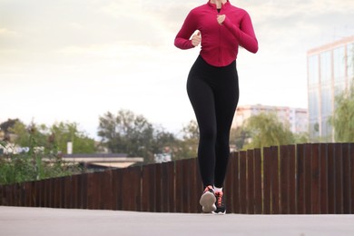 Photo of Woman in sportswear running outdoors, closeup. Space for text