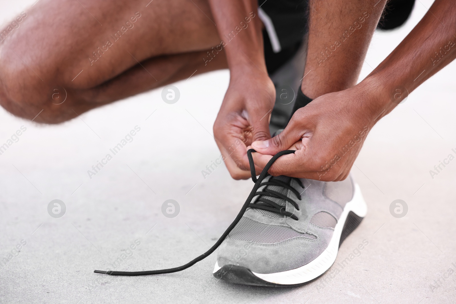 Photo of Runner tying shoelace of his sneaker outdoors, closeup