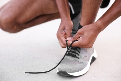 Photo of Runner tying shoelace of his sneaker outdoors, closeup