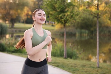 Photo of Smiling woman in sportswear running outdoors. Space for text