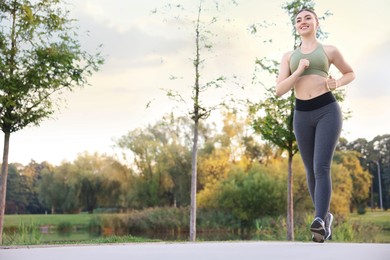 Photo of Smiling woman in sportswear running outdoors, low angle view. Space for text