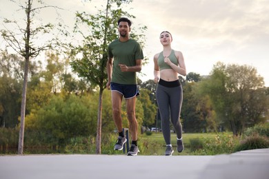 Photo of Sporty couple running outdoors, low angle view