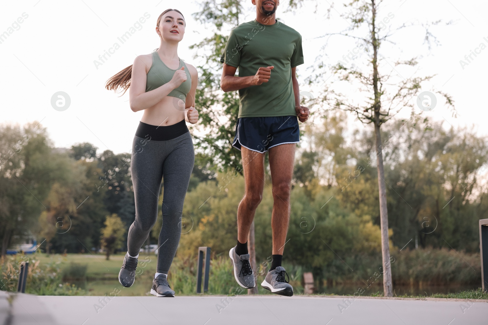 Photo of Sporty couple running outdoors, closeup and low angle view
