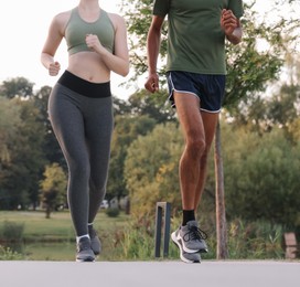 Photo of Couple in sneakers running outdoors, closeup. Healthy lifestyle