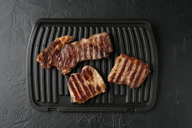 Photo of Delicious grilled beef meat on black textured table, top view