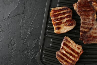 Photo of Delicious grilled beef meat on black textured table, top view. Space for text