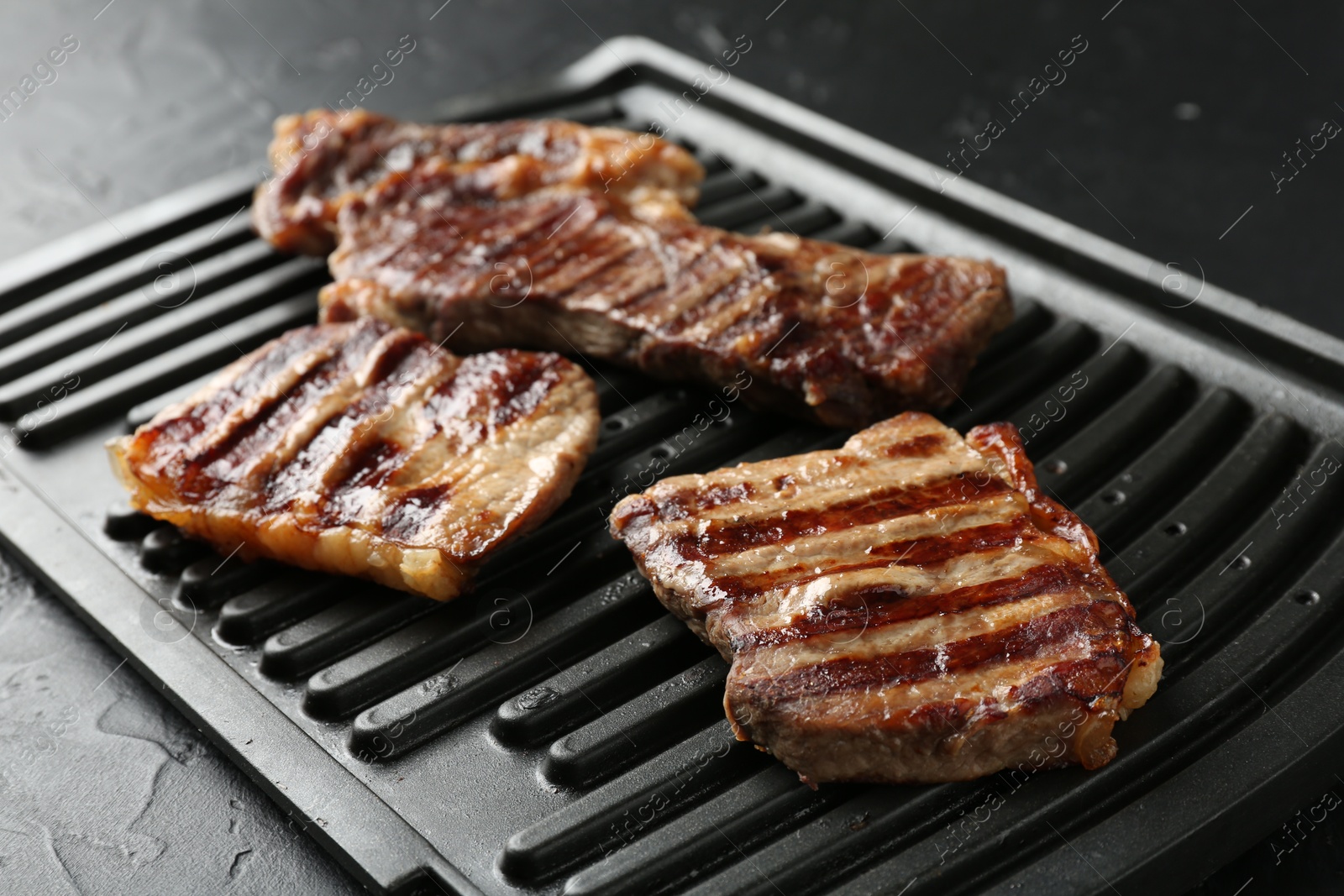 Photo of Delicious grilled beef meat on black textured table, closeup
