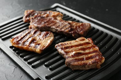 Photo of Delicious grilled beef meat on black textured table, closeup