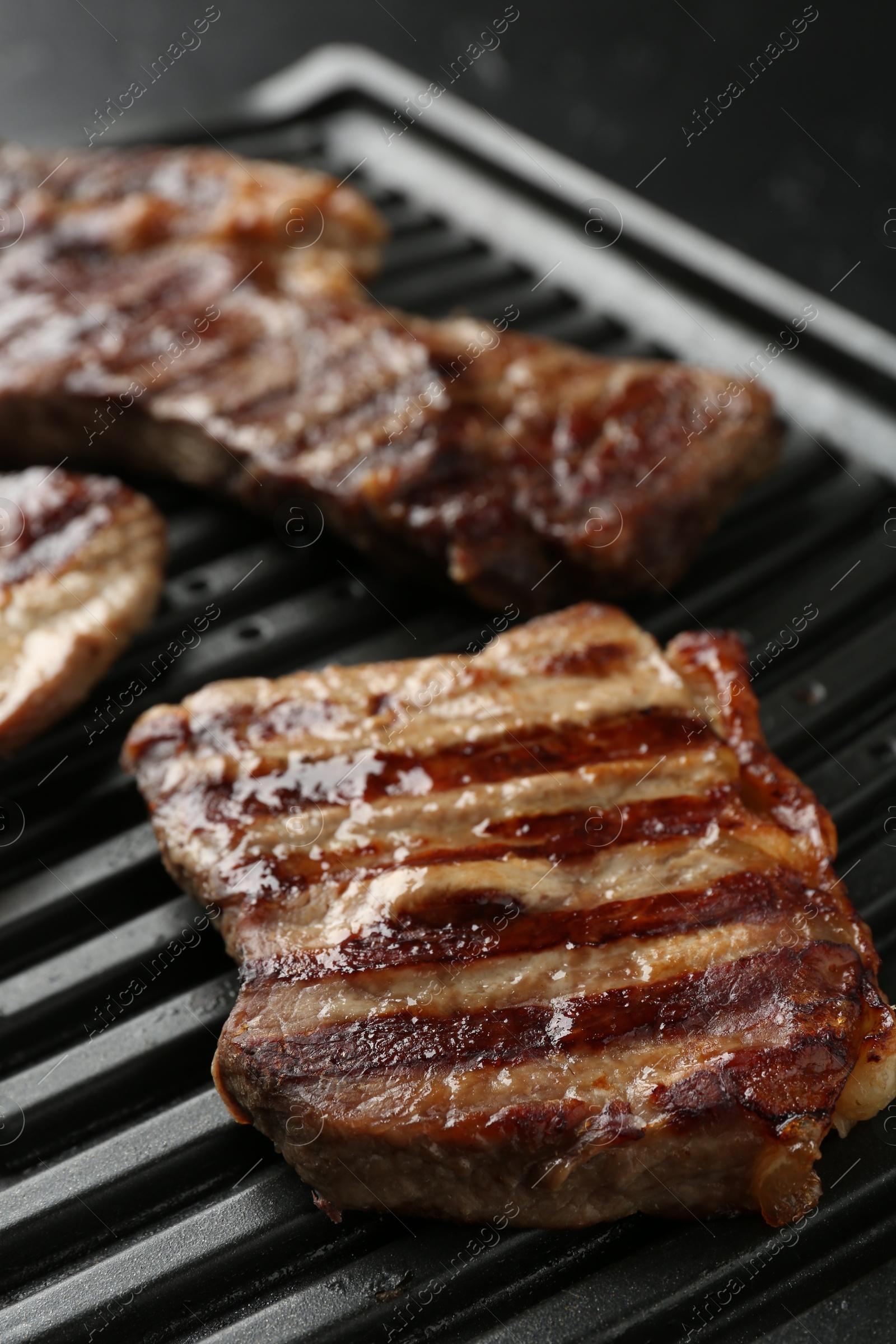 Photo of Electric grill with delicious beef meat on table, closeup