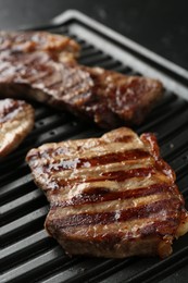 Photo of Electric grill with delicious beef meat on table, closeup