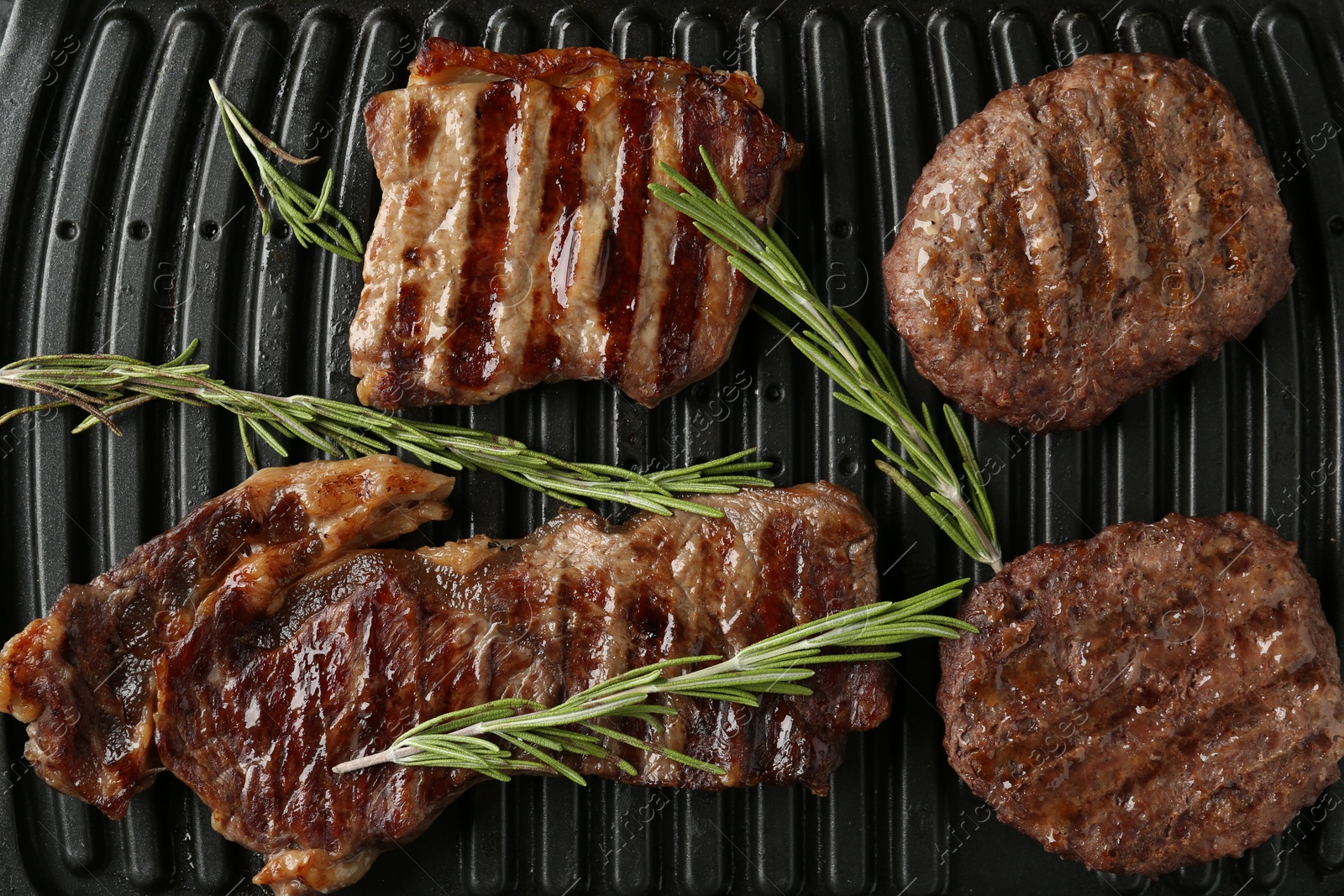 Photo of Electric grill with beef meat and rosemary, top view