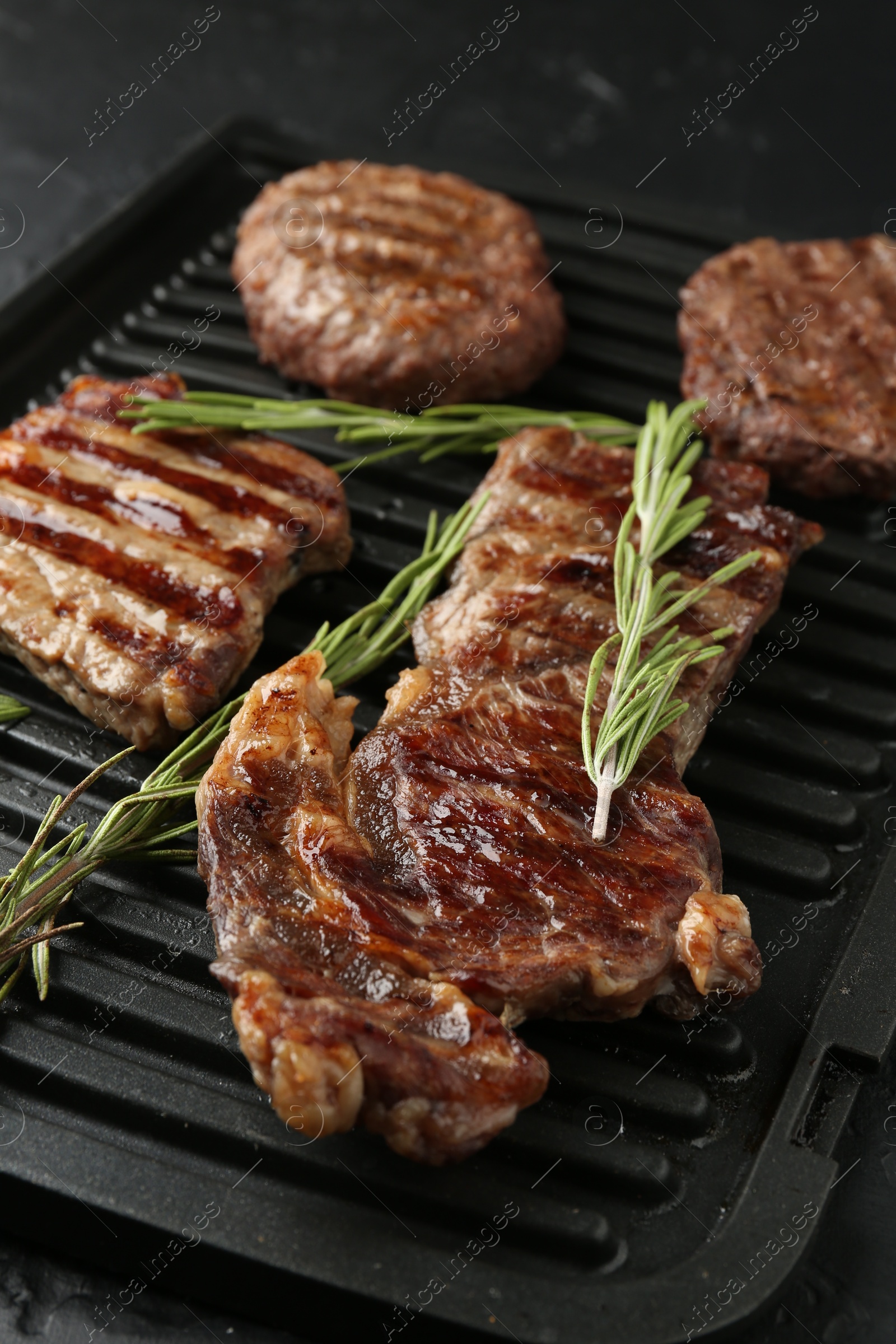 Photo of Delicious grilled beef meat with rosemary on black table, closeup