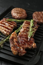 Photo of Delicious grilled beef meat with rosemary on black table, closeup