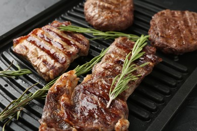 Photo of Delicious grilled beef meat with rosemary on black table, closeup