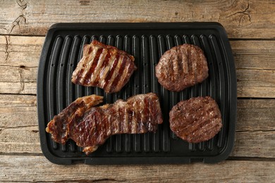 Photo of Delicious grilled beef meat on wooden table, top view